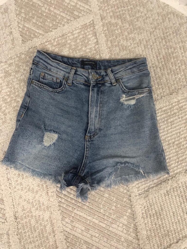 Mavi denimden yapılmış, gevşek kesim ve kısa boyda, yıpranmış detaylar